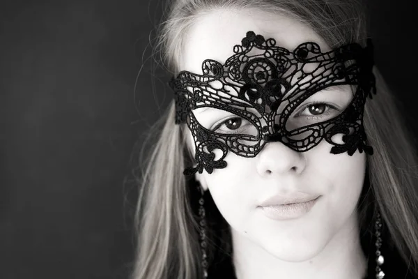 Model with a flowing hair and a black openwork mask on a face — Stock Photo, Image