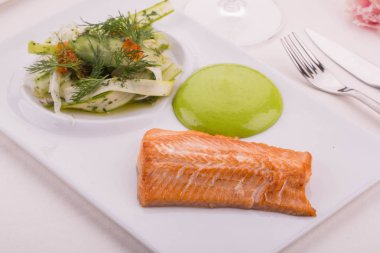 Fileto bir somon, pırasa ve rezene ve salatalık salatası krema ile servis edilir