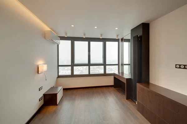 Panoramic windows in the light bedroom with a brown wooden floor