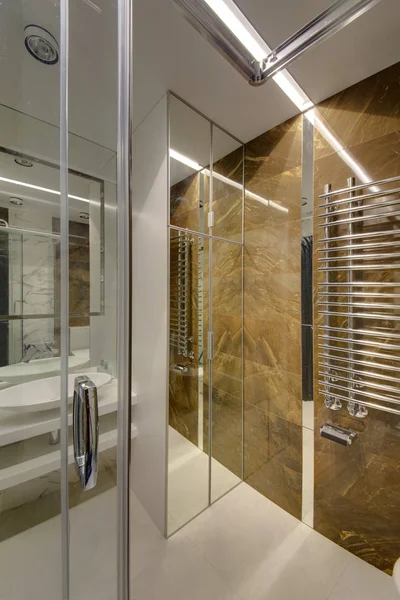 A mirror bathroom with a shower cabin and light walls