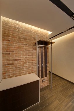 Brick kırmızı bir duvar ve başucundaki ayakkabı için bağlı askı bir salonu