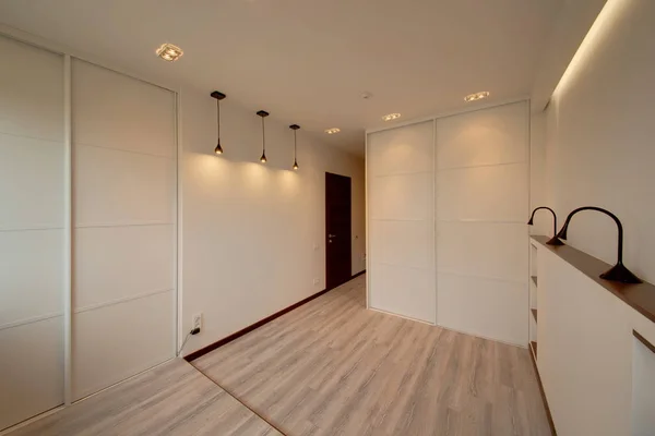 The light white bedroom with the white built-in sliding wardrobes and lamps