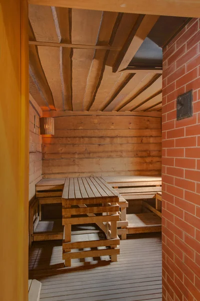 A steam room with wooden plank beds and a brick wall