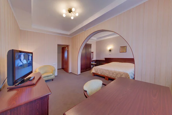 The bedroom from a hall, a curbstone with the TV set, easy chairs, a big bed, a wooden cabinet