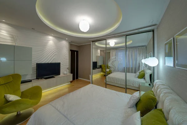 The light big bedroom with a mirror case, the TV, pillows and a chair