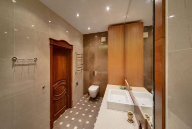 Bir banyo bir tuvalet, ahşap bir kapı, bir ayna, bir lavabo, çok renkli bir yerde döşeme