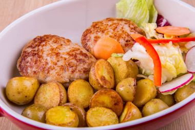 Kızarmış tavuk pirzola ile pişmiş pass patates, sebze salatası ile servis edilir