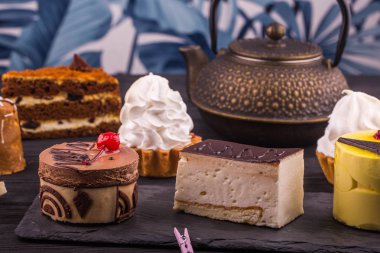 Bir sufle, pasta ve kek, küçük sepet ve bir demlik çay ile