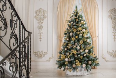 Noel ağacı beyaz sepetin içinde, içinde altın süslemeler var.