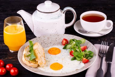 İki yumurtalı kahvaltı, el bombası ve portakal suyu ile servis edilen domates.