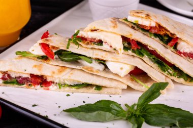 Tonbalığı, mozzarella, kırmızı soğan, domates ve krem peynirli piadina kahvaltıda servis edilir.