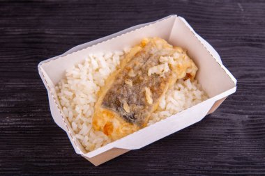 Tek kullanımlık tabakta haşlanmış pilav ve kızarmış balık.
