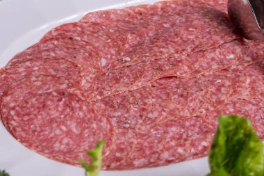 Bir tabak yeşillikte porsiyon sosis.