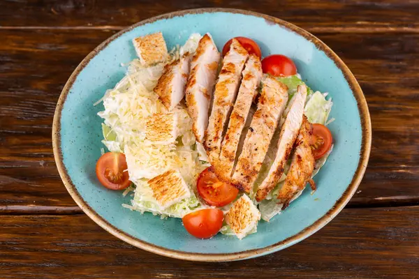 Salad with chicken, tomatoes and grenks, with lettuce leaves and grated cheese