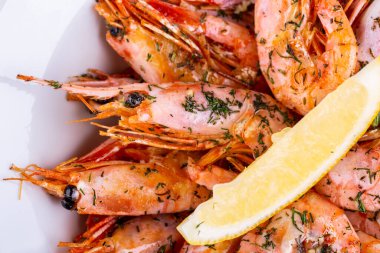 Yeşillikli haşlanmış karides ve limon dilimi.