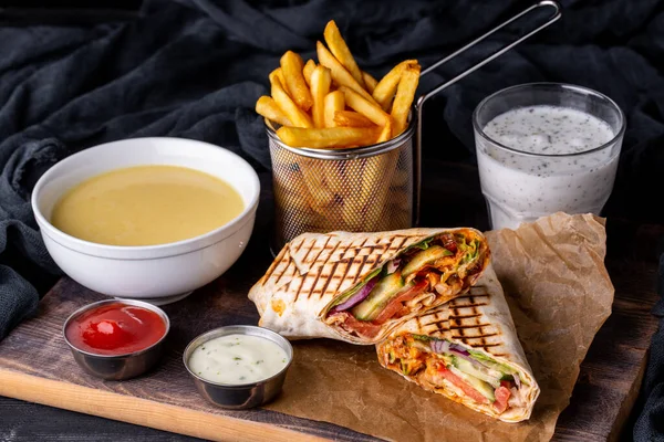 Dener sauces in a tortilla, served with cream sauce, ketchup, puree soup, fries and a glass of kefir