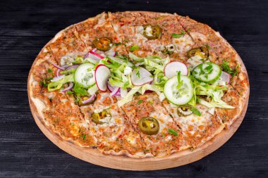 Kıyma, sebze ve peynirli pizza fırında, salata ve taze sebzelerle servis ediliyor.