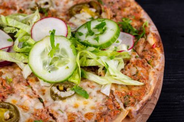 Kıyma, sebze ve peynirli pizza fırında, salata ve taze sebzelerle servis ediliyor.