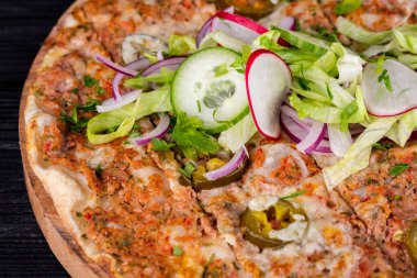 Kıyma, sebze ve peynirli pizza fırında, salata ve taze sebzelerle servis ediliyor.