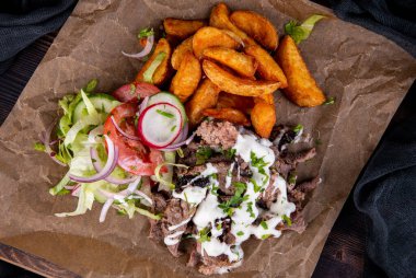 Peynir soslu trochanter eti, ev yapımı patates, taze sebze, domates, salatalık, turp ve soğanla servis edilir.