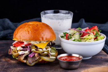 Sığır etli hamburger eti, ketçap, taze salata ve kefir soslu bardak.
