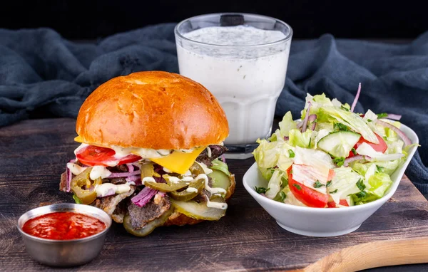 Hamburger meat with beef, ketchup, fresh salad and glass with kefir