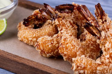 Sos ve limon ile servis edilen ekmek kırıntıları içinde kraliyet karidesi.