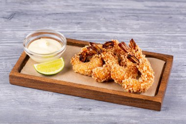 Sos ve limon ile servis edilen ekmek kırıntıları içinde kraliyet karidesi.