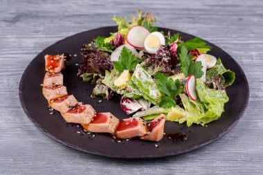 Taze salata ve bıldırcın yumurtası ile servis edilen susamlı ızgara ton balığı.