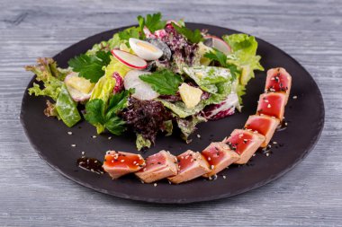 Taze salata ve bıldırcın yumurtası ile servis edilen susamlı ızgara ton balığı.