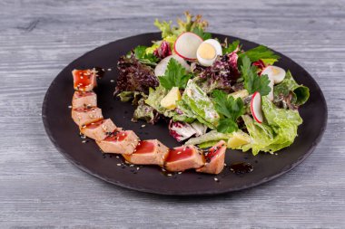 Taze salata ve bıldırcın yumurtası ile servis edilen susamlı ızgara ton balığı.