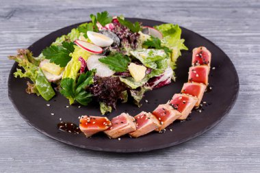 Taze salata ve bıldırcın yumurtası ile servis edilen susamlı ızgara ton balığı.