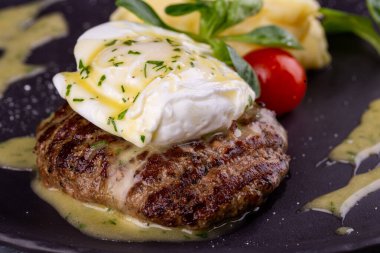 Yumurtalı bir parça biftek, patates püresi ve sebzeli vişneli domates.