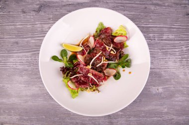 Terriaki soslu sıcak biftek salatası, turp, limon ve taze salata ile servis edilir.