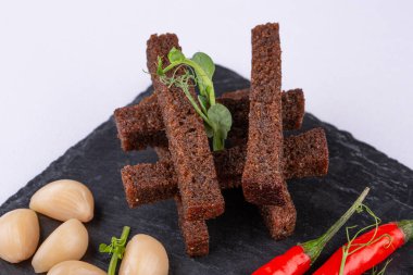 Et tabağı sert ve tütsülenmiş et, ekmek kırıntıları, sarımsak ve turşulu biber ile servis edilir.