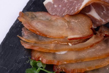 Et tabağı sert ve tütsülenmiş et, ekmek kırıntıları, sarımsak ve turşulu biber ile servis edilir.