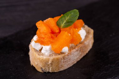 Siyah arka planda balık, et ve sebzeli çeşitli tost kanapeleri.