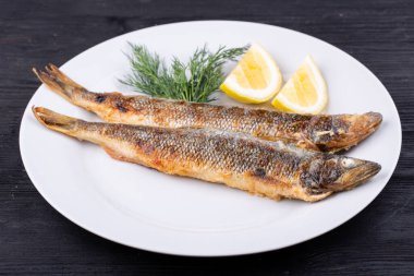 Izgarada kızarmış uskumru, limon ve dereotuyla servis edilir.