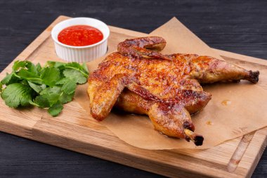 Kömürde kızartılmış tavuk tütünü sarımsaklı, yeşillik ve ketçapla servis ediliyor.