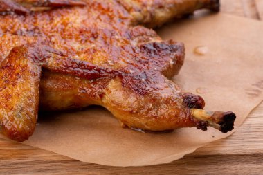 Kömürde kızartılmış tavuk tütünü sarımsaklı, yeşillik ve ketçapla servis ediliyor.