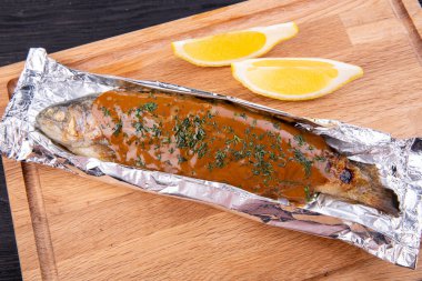 Soslu ve otlu folyoda pişmiş alabalık.