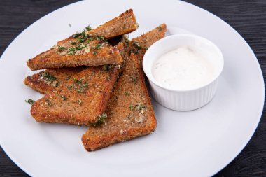 Yeşillik ve krema sosuyla servis edilen siyah ekmekten sarımsaklı ızgara.