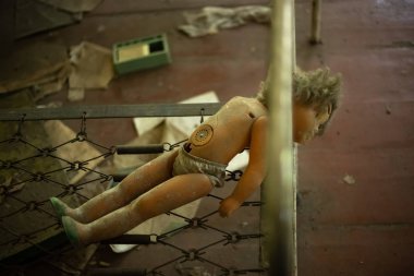 Terk edilmiş anaokulundaki çocukların yatağında kırık bir bebek.