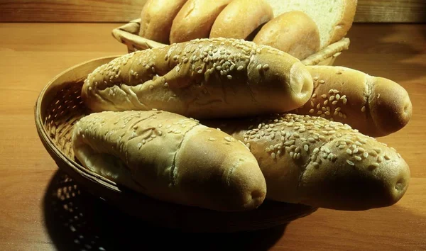 在面包店的木桌上放在面包篮里的各种面包卷 — 图库照片