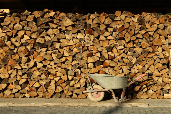 Stapel Brennholz Und Schmutzige Schubkarre — Stockfoto