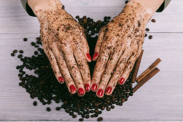 Female hands with red manicure and coated coffee scrub