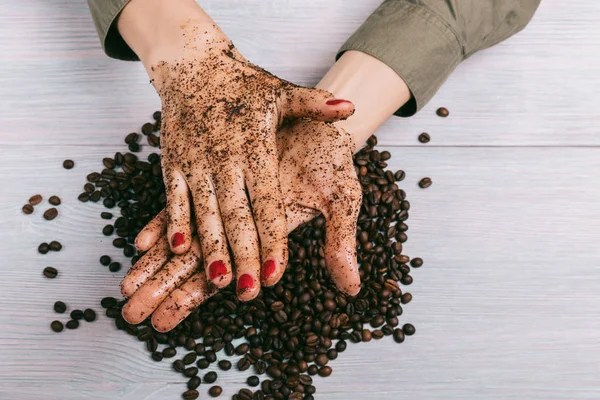 Woman applies coffee scrub on hands