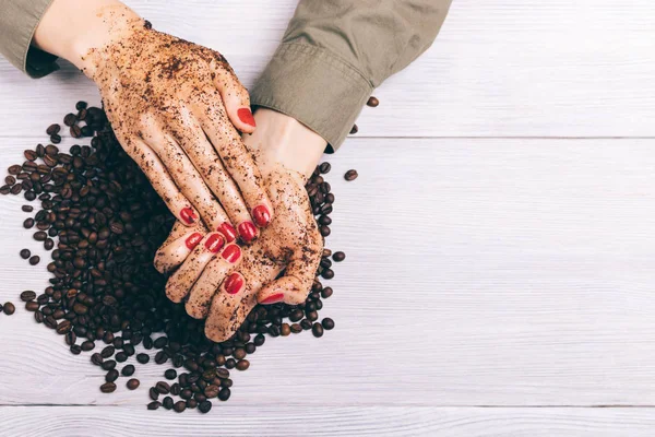 Close-up of a woman applying coffee scrub to her hands
