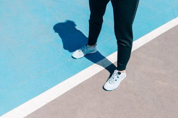 Cropped image of female legs in sneakers and black pants standin