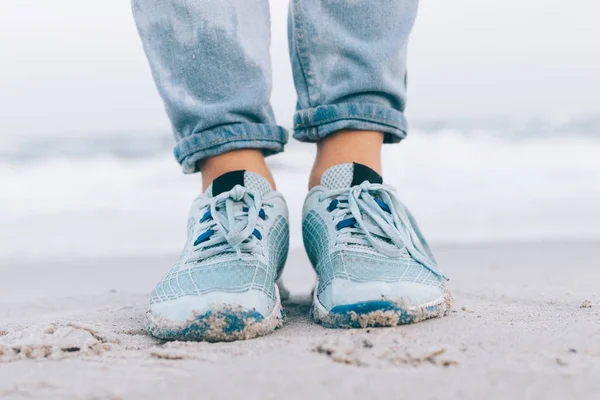 Female feet in wet jeans and sneakers
